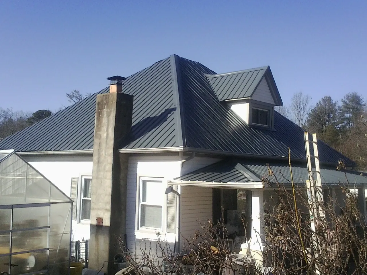 Dark blue standing seam metal roof on a white farmhouse with dormer — Slate & Tile Roof Repair by Roofing Brothers in Tenino