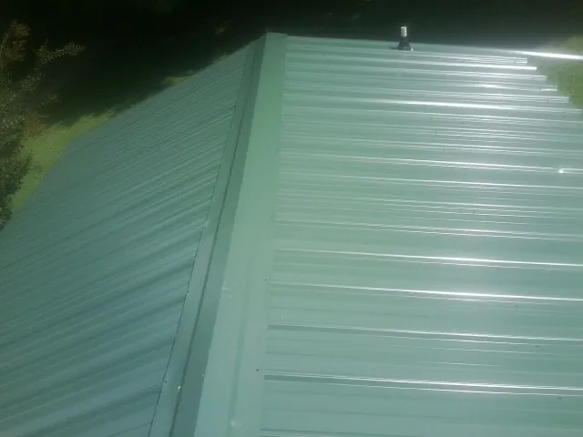 New green metal panels meeting at the ridge of a roof — Flat Roof Repair work by our crew in Tenino