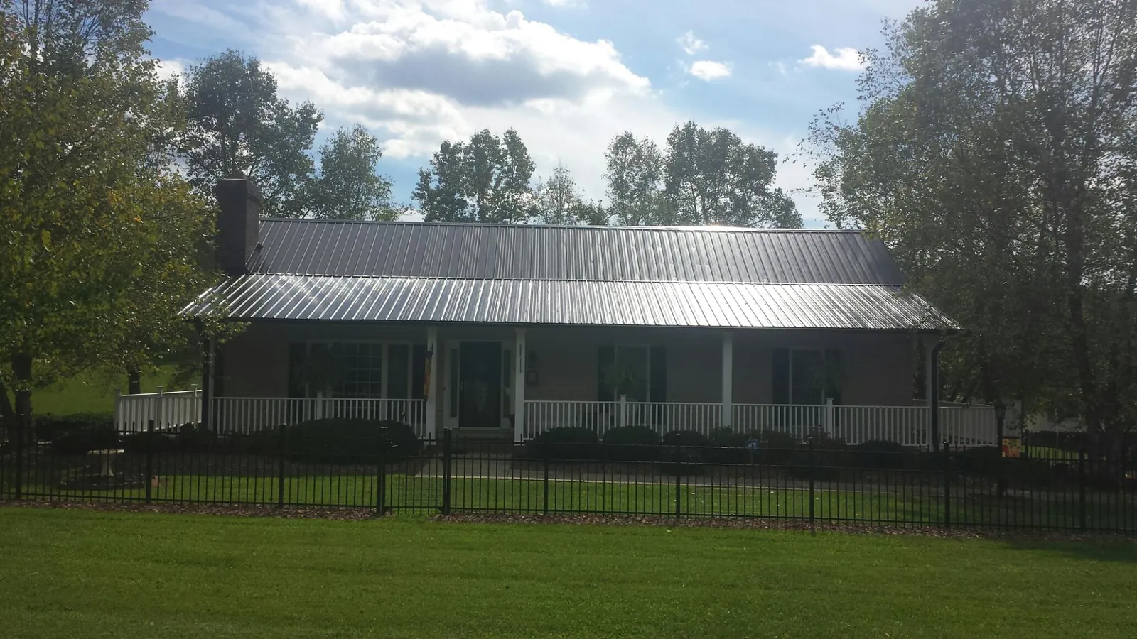 Gray metal roof on a brick ranch with a full width front porch — Gutter Guard Installation work by our crew in Tenino