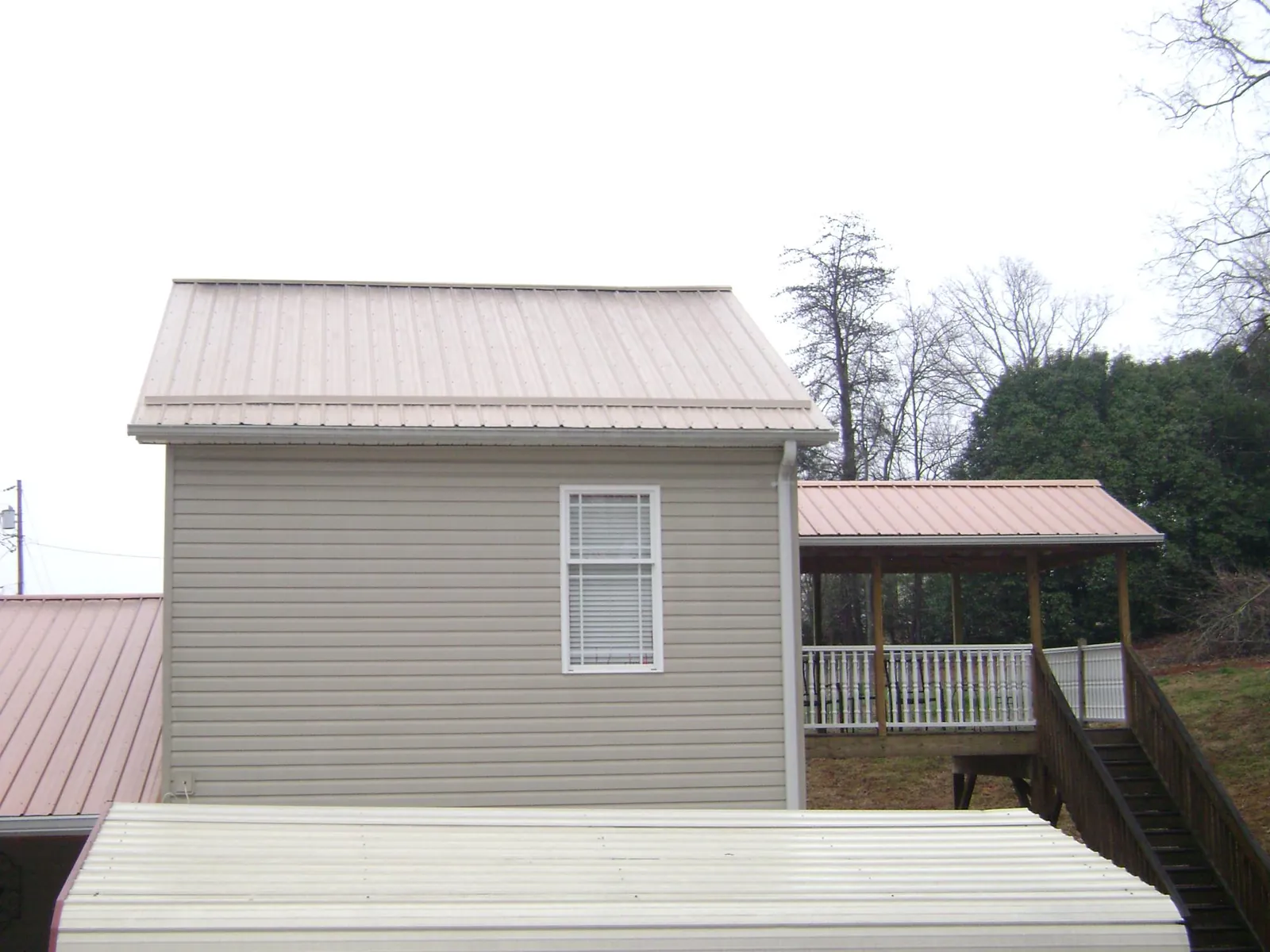 Tan metal roofs on a two story addition and attached porch, from a Roof Replacement job in Tenino