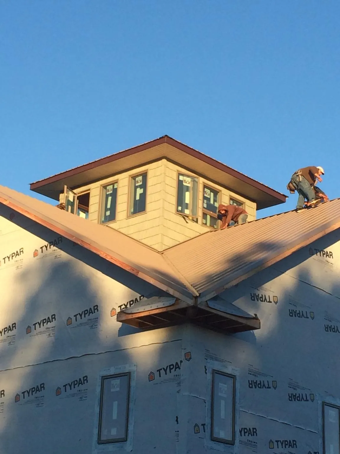 Roofers working around a rooftop cupola on a new metal roof at sunset — Roof Waterproofing in Tenino by Roofing Brothers